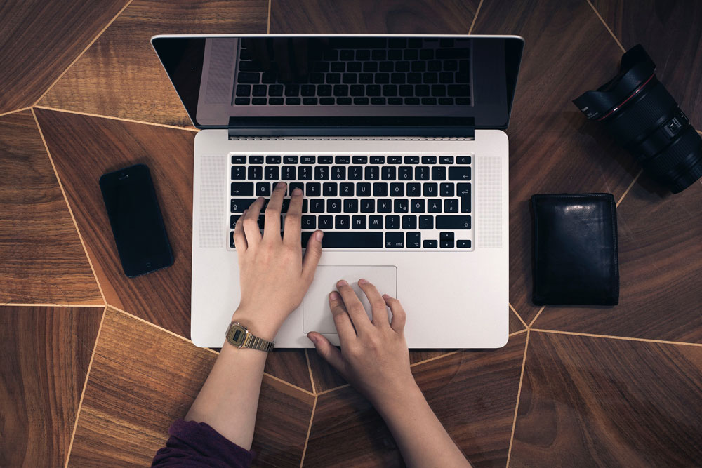 A persons hands on a laptop keyboard